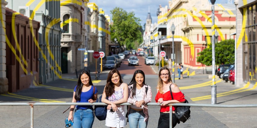 a group of students are in fremantle smiling on a bridge 