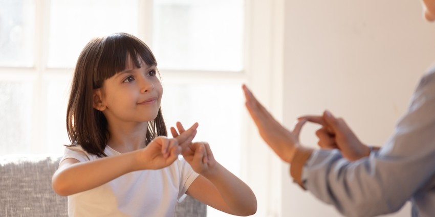 A young girl using sign language.