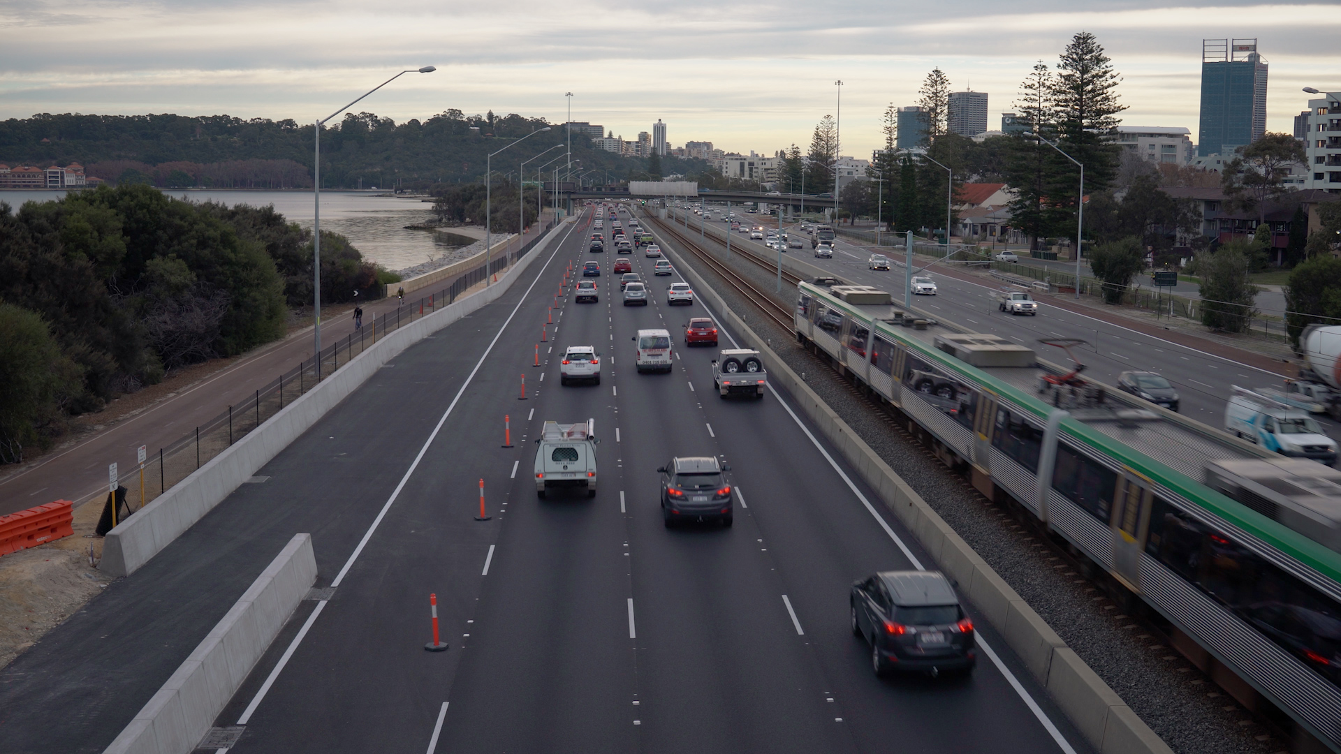 Vehicles on freeway next to a passing passenger train