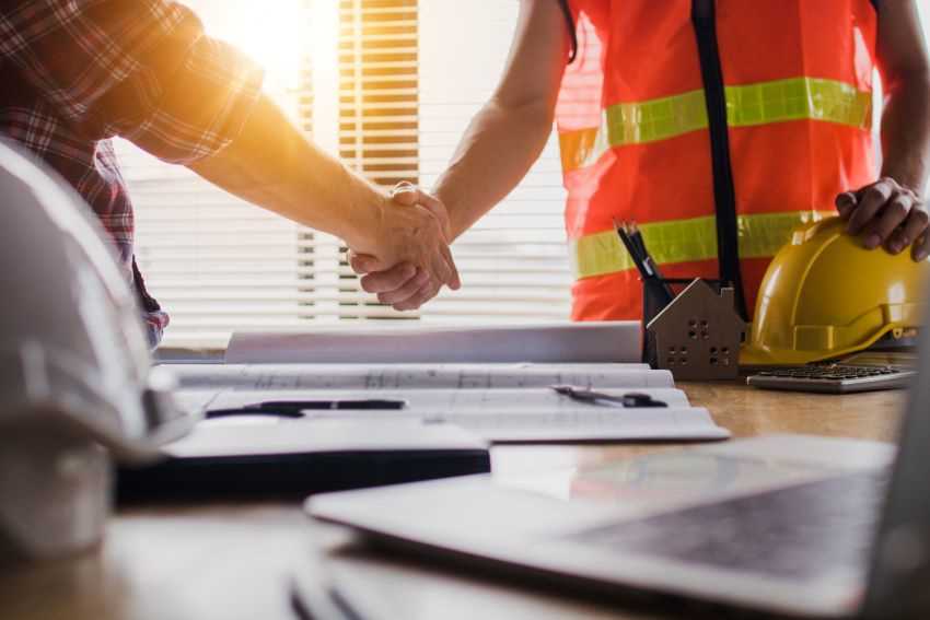 Construction workers shaking hands over a document