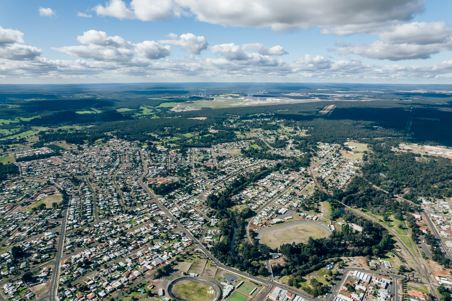 A birds eye view of Collie with rolling green hills and blue sky along with a town centre