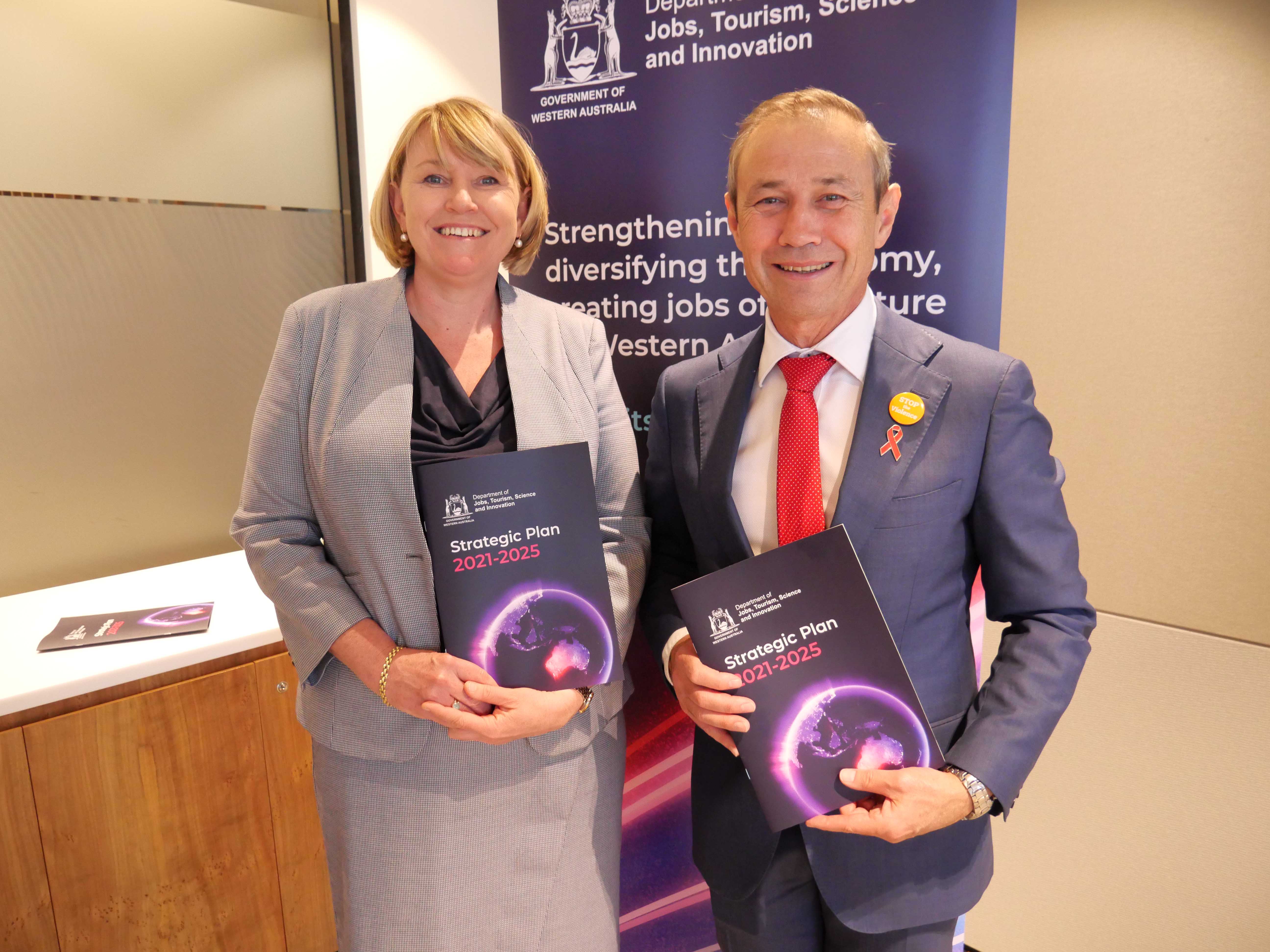 Director General Rebecca Brown and Deputy Premier Roger Cook facing the camera and both holding the JTSI Strategic Plan