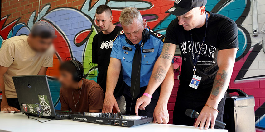 Deputy Commissioner for Women and Young People, Andy Beck, joins detainees in a music composing lesson with rapper Optamus (right) in the Banksia Beats Music Studio.