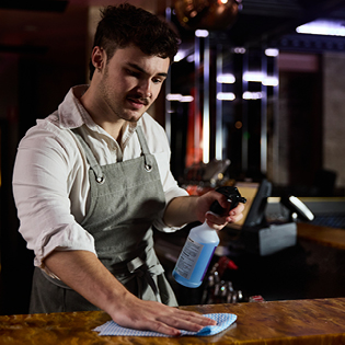 A bartender sanitising the bar