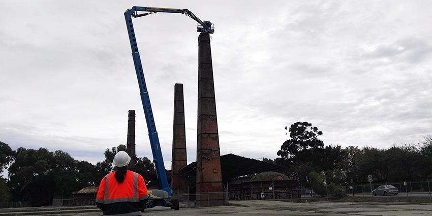 A construction worker looking up at a crane and building