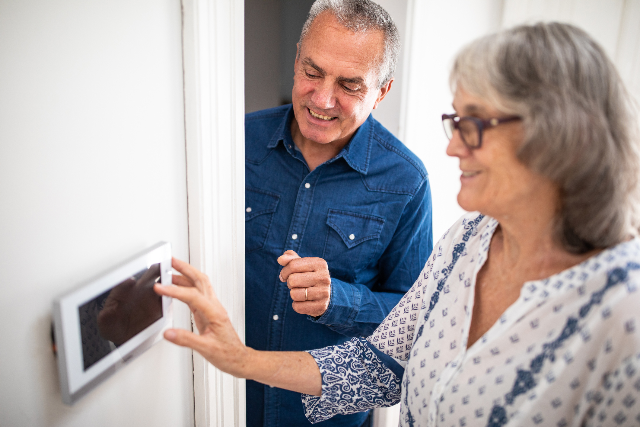 An older couple using an electric wall panel.