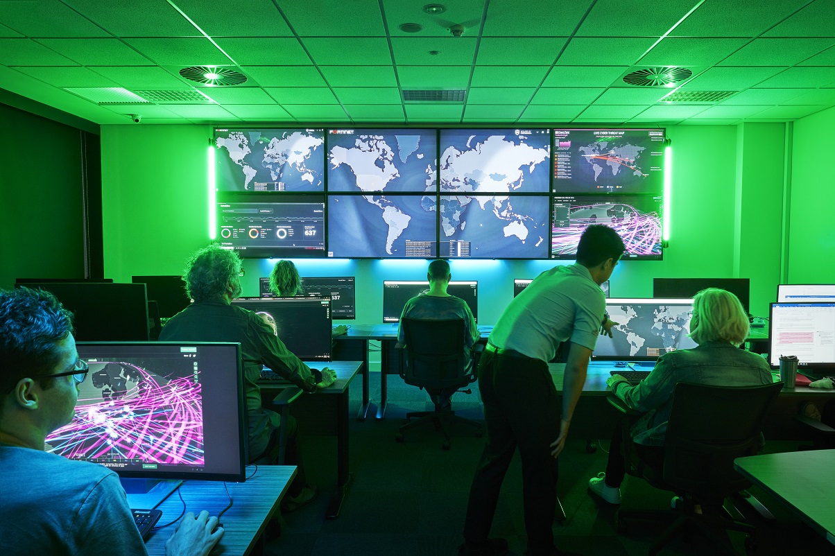 People at computers looking at large screen 