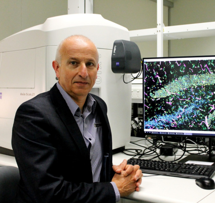 A portrait of Professor John Mamo sitting at a computer 
