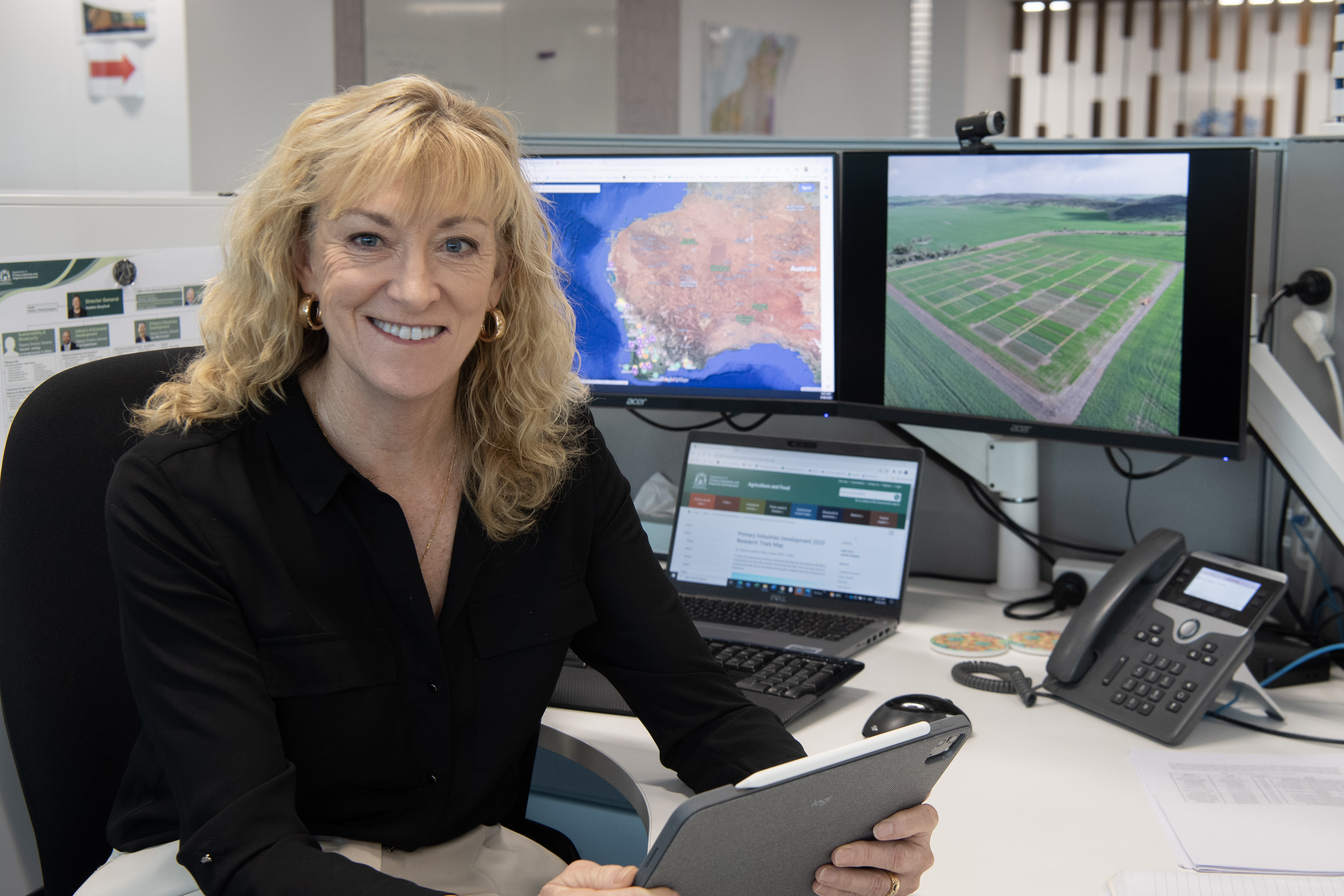 Grains Director Kerry Regan at office desk looking over grains trial map