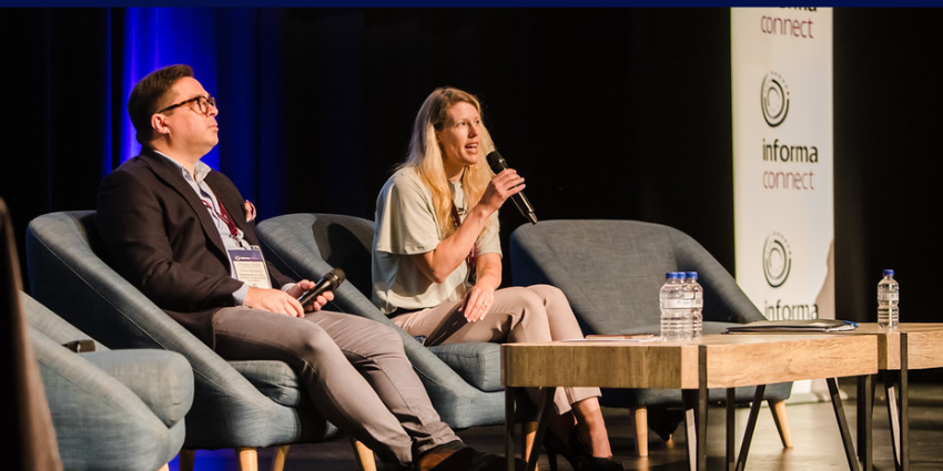 Landscape photo of a panel discussion at the 2023 Pilbara Summit. Katie Cook is holding a microphone and talking to the crowd. Beside her is Chris Schooling.