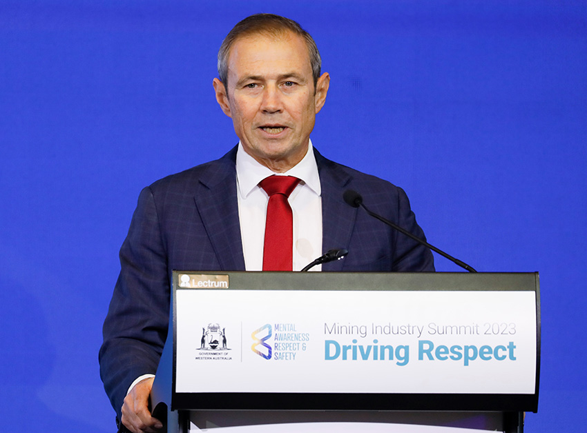 Man in a suit with a red tie addresses the summit