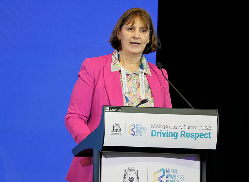 Woman in pink jacket addresses the summit