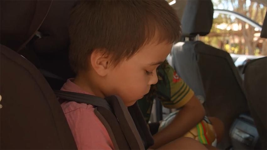 child in the backseat of a car wearing a seatbelt
