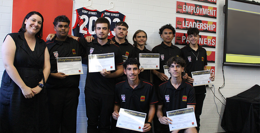 a group of people standing against a wall holding certificates