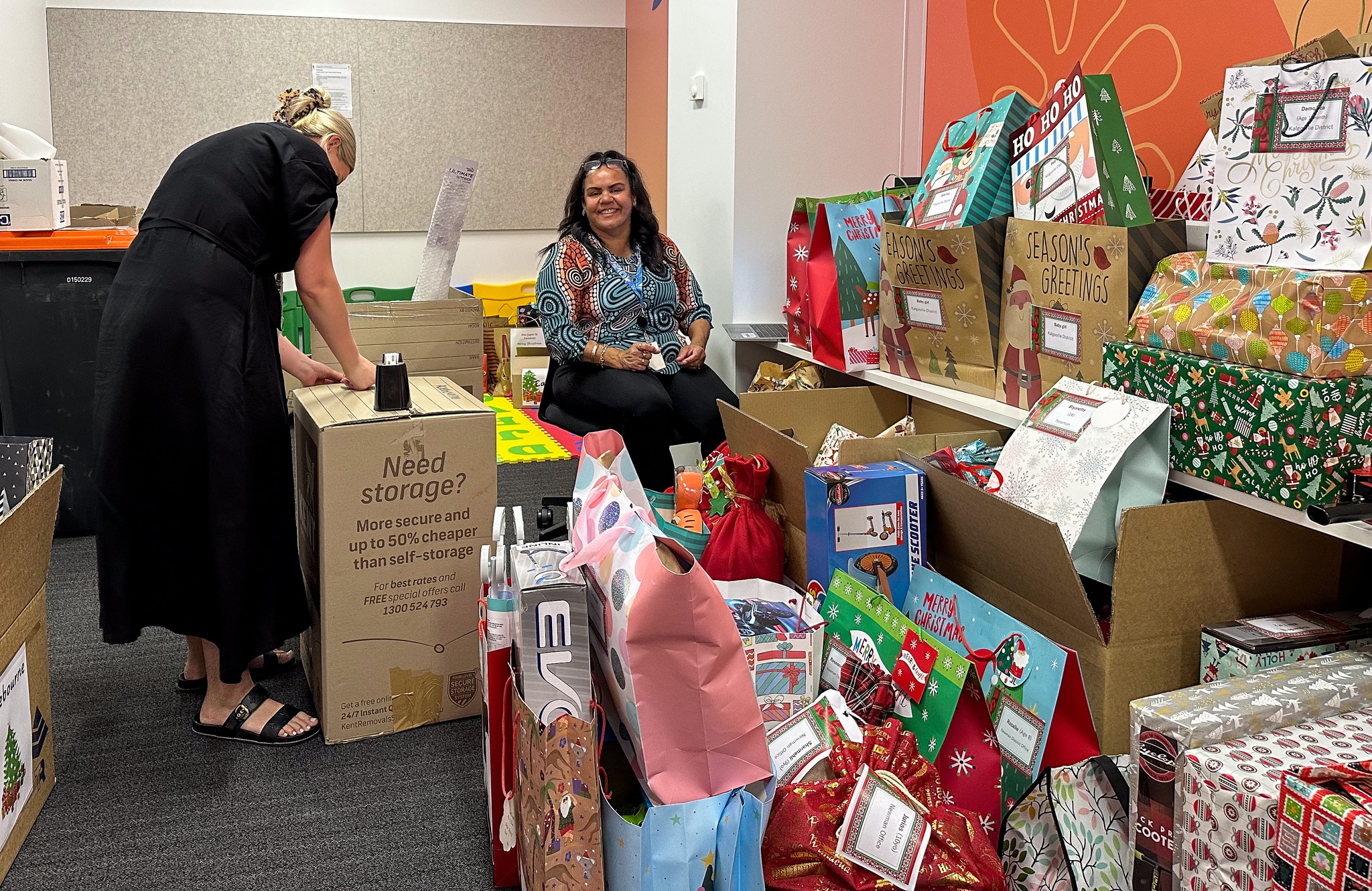 Photo of two Communities staff members wrapping and packing Christmas presents