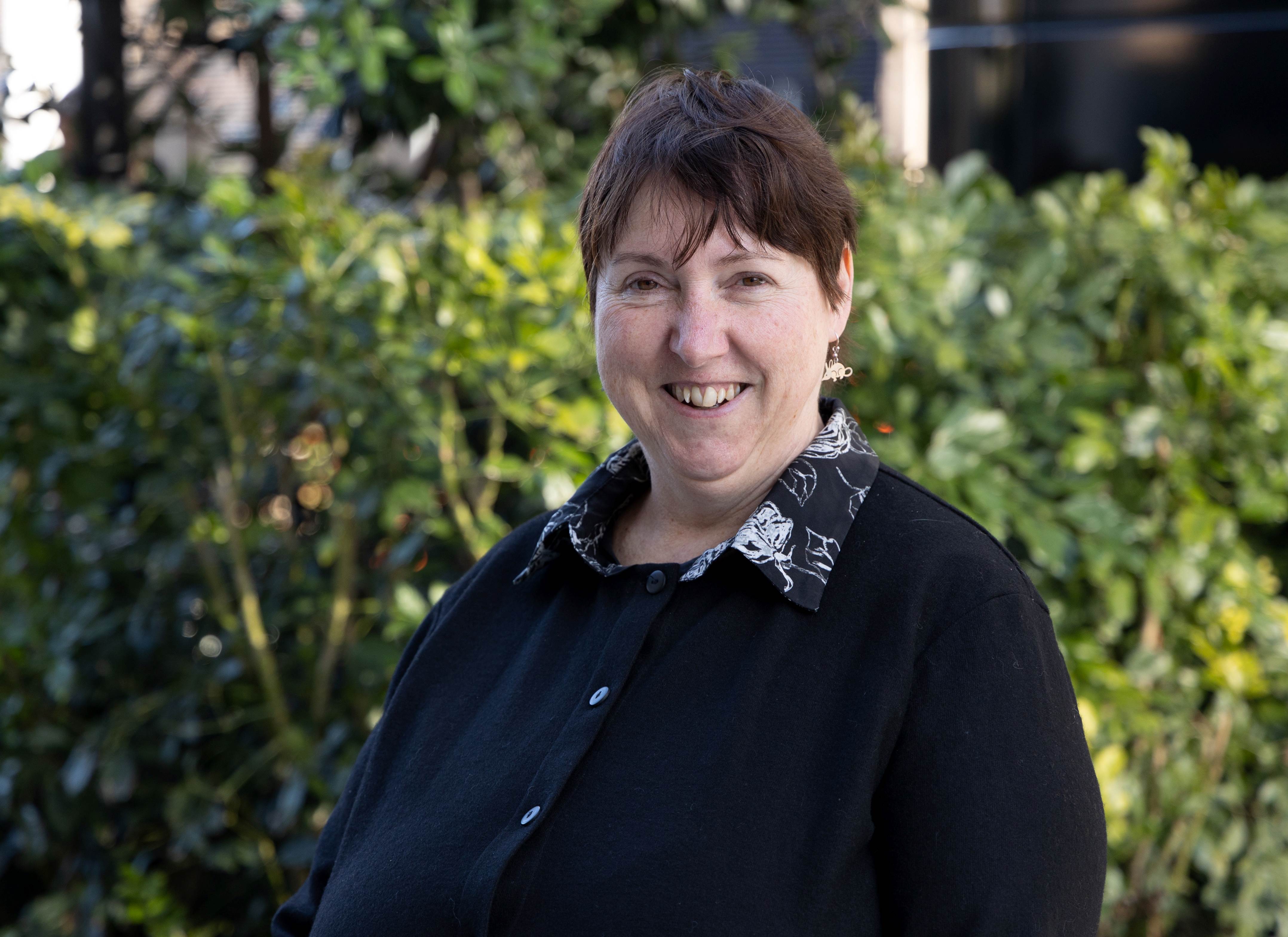 A woman standing in from of foliage. 