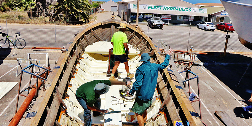 Prisoners from Greenough Regional Prison paint the Batavia longboat's decking during restoration work.
