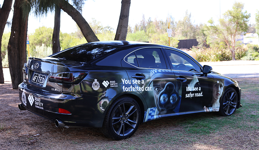 a black car covered with road safety messaging parked next to a tree