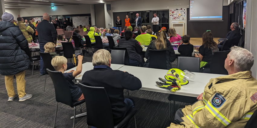 A room full of people, with the Commissioner talking at the front of the room