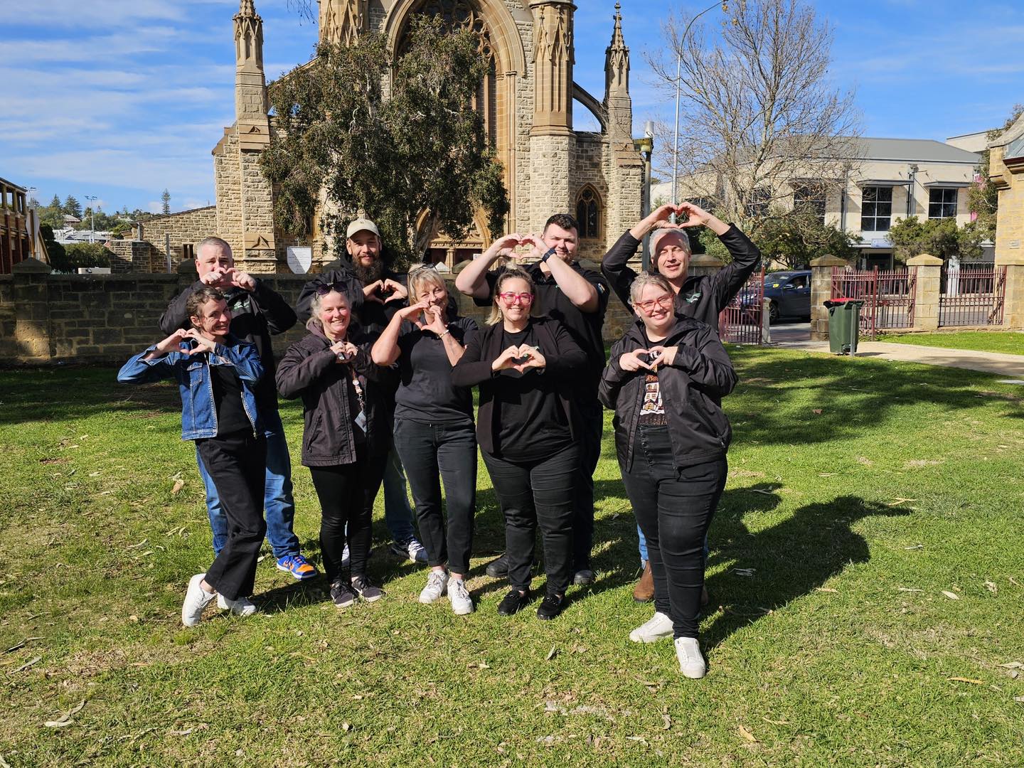 Photo of a group of people making the heart symbol with their hands