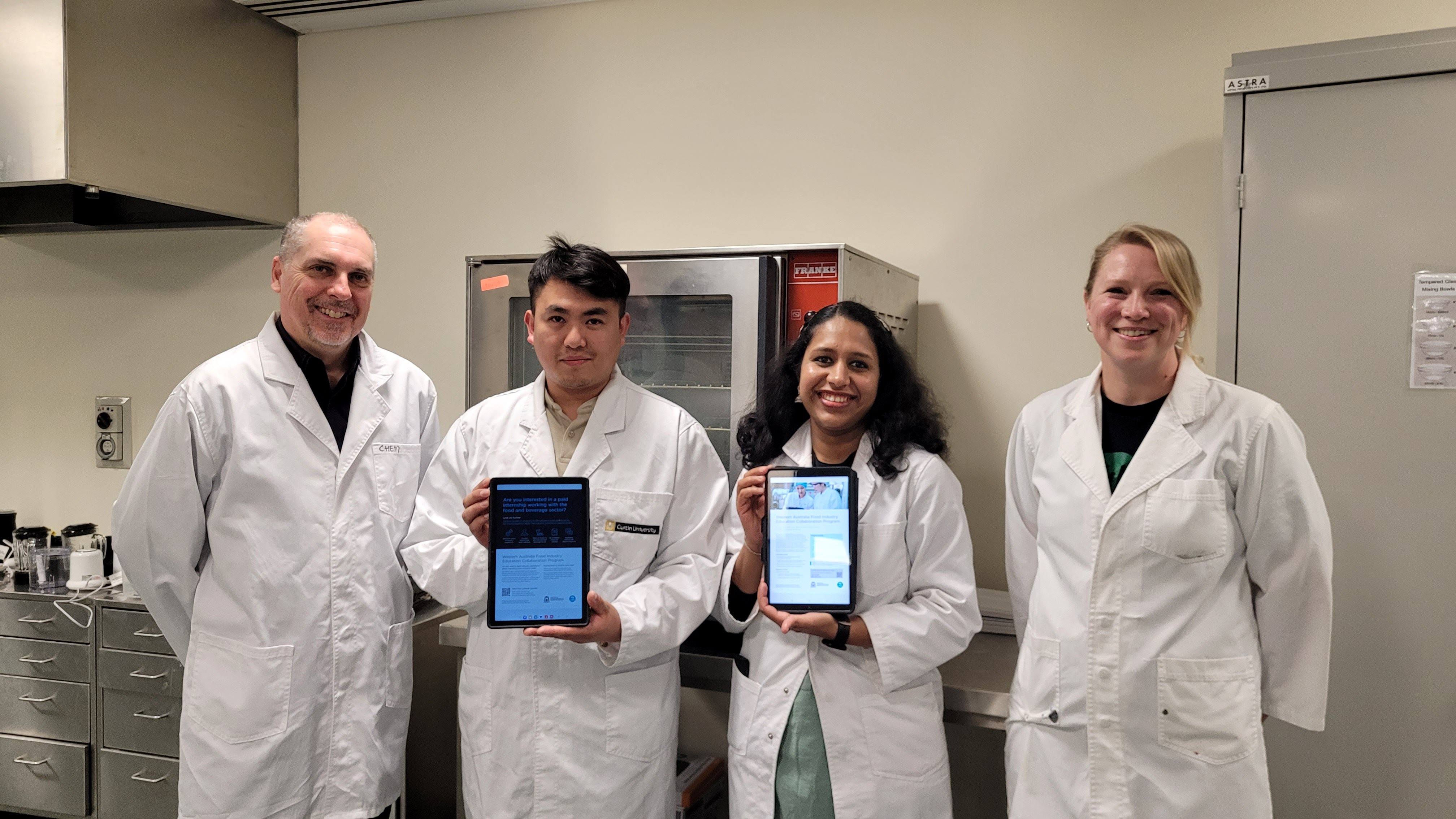 Four people in white laboratory coats in food laboratory.