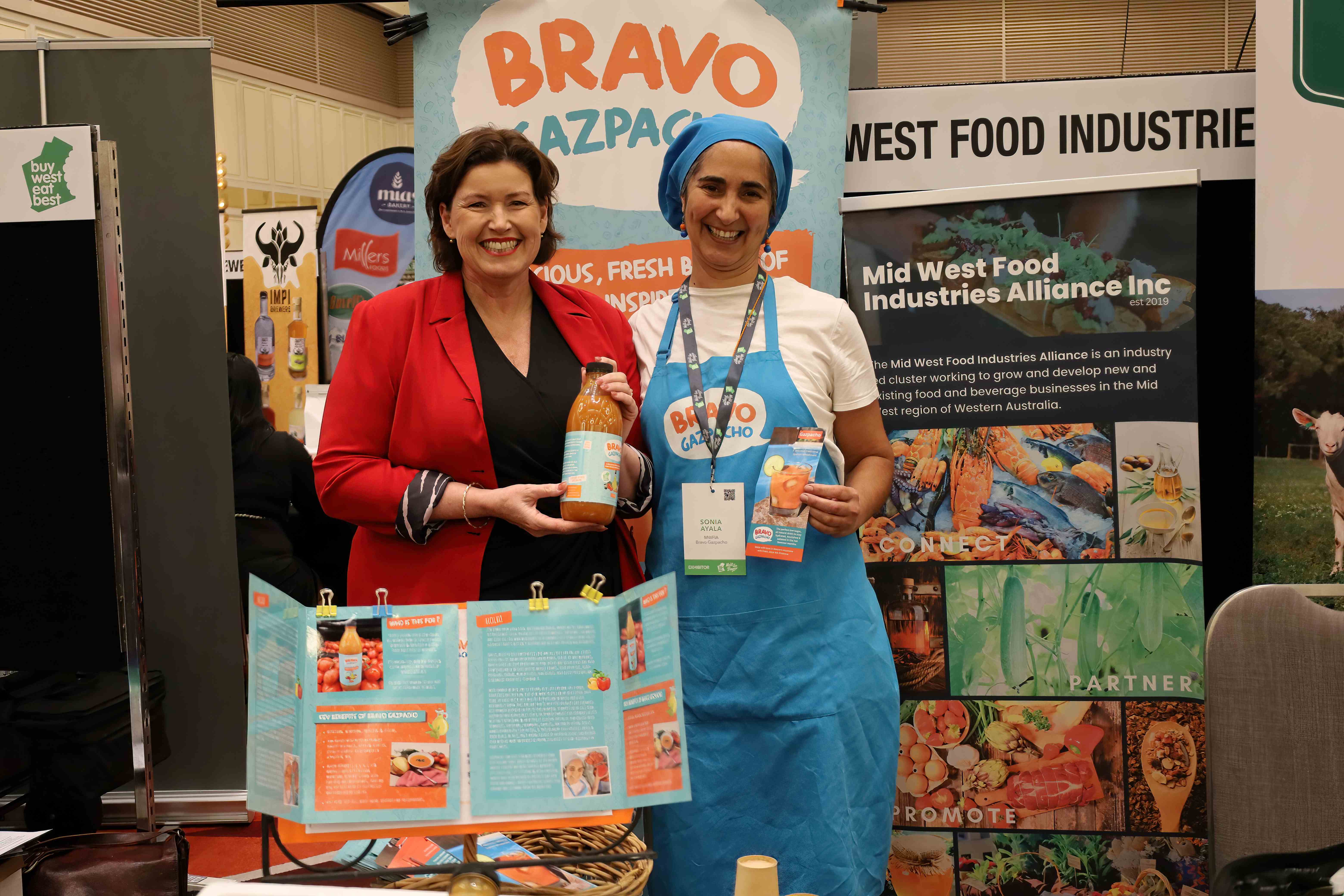Two women holding a soft drink botting in a promotional display.