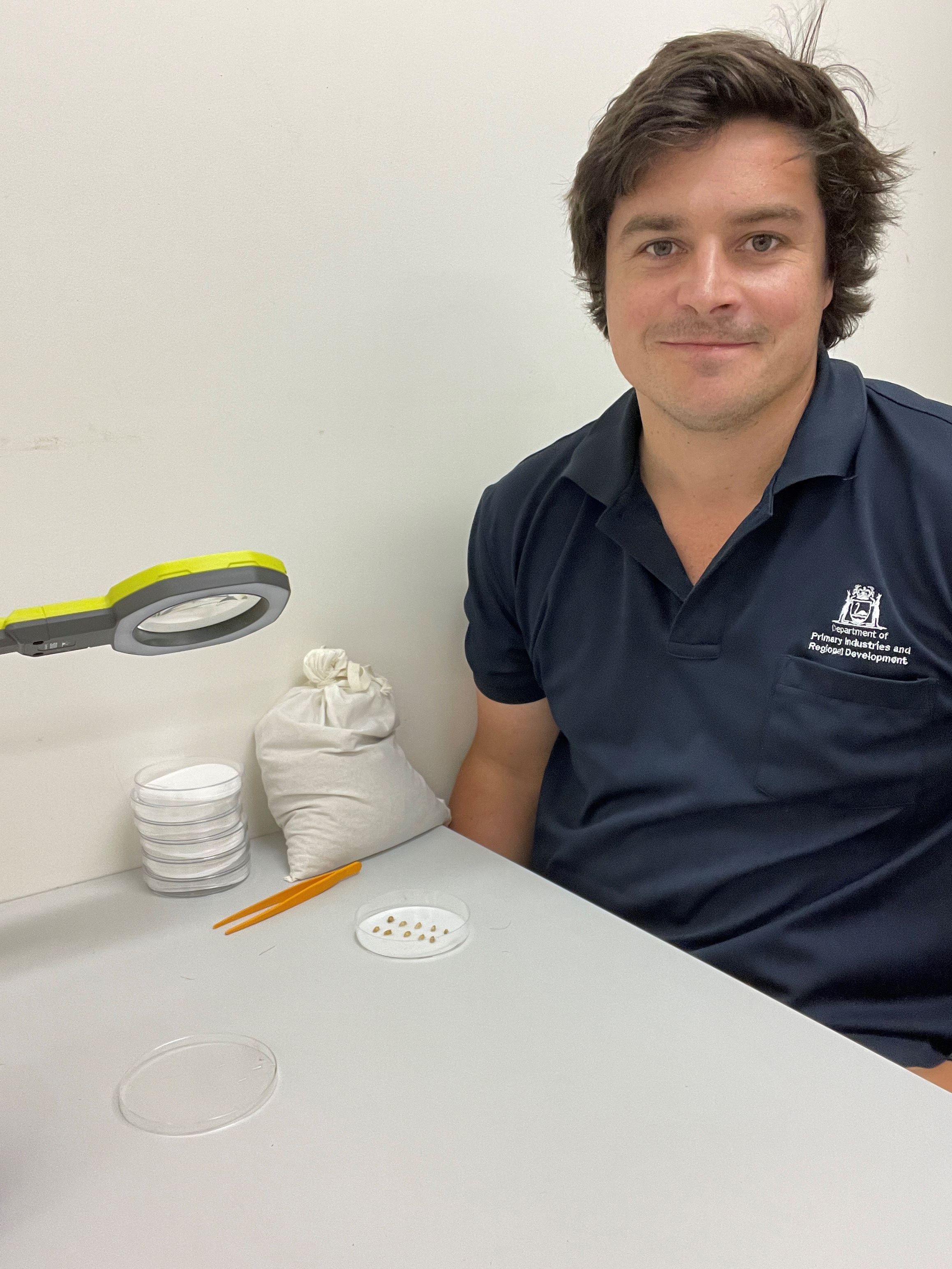 A man siting at a desk with a petri dish.