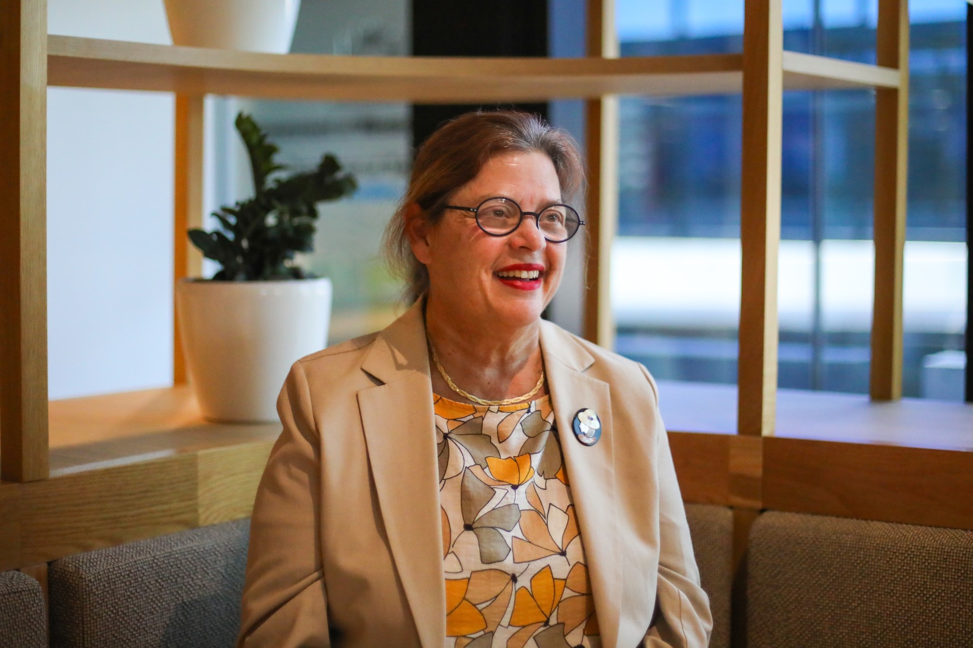 Image of a a professional staff member at Communities, smiling in an office environment. She is Acting Chief Legal Officer, Tara Gupta.