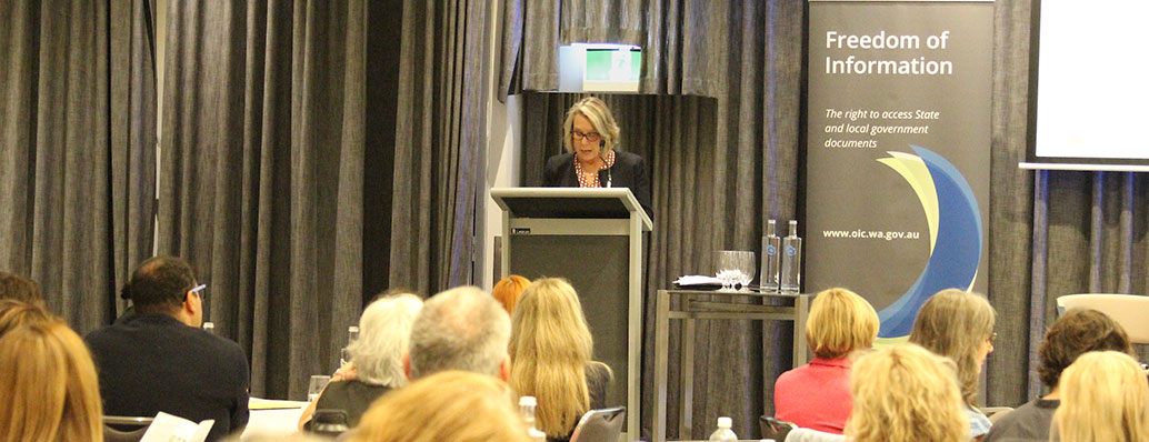 Woman talking into a microphone on a stand in front of the audience