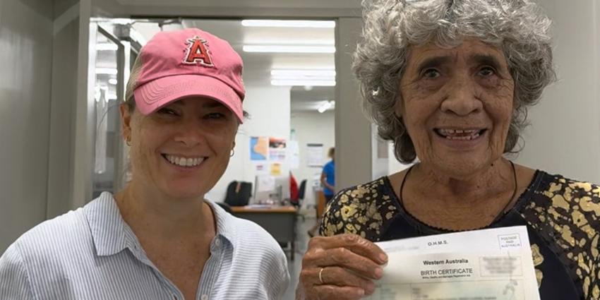 Woman in pink cap next to a woman holding a birth certificate