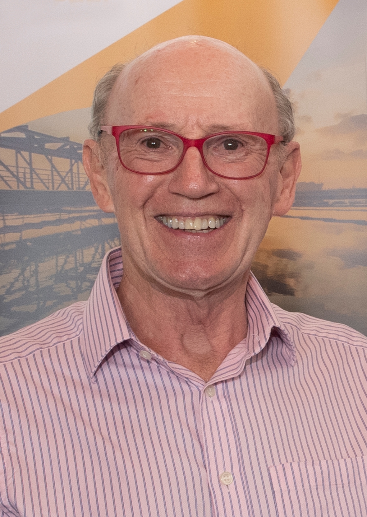 A smiling mature man with red glasses.