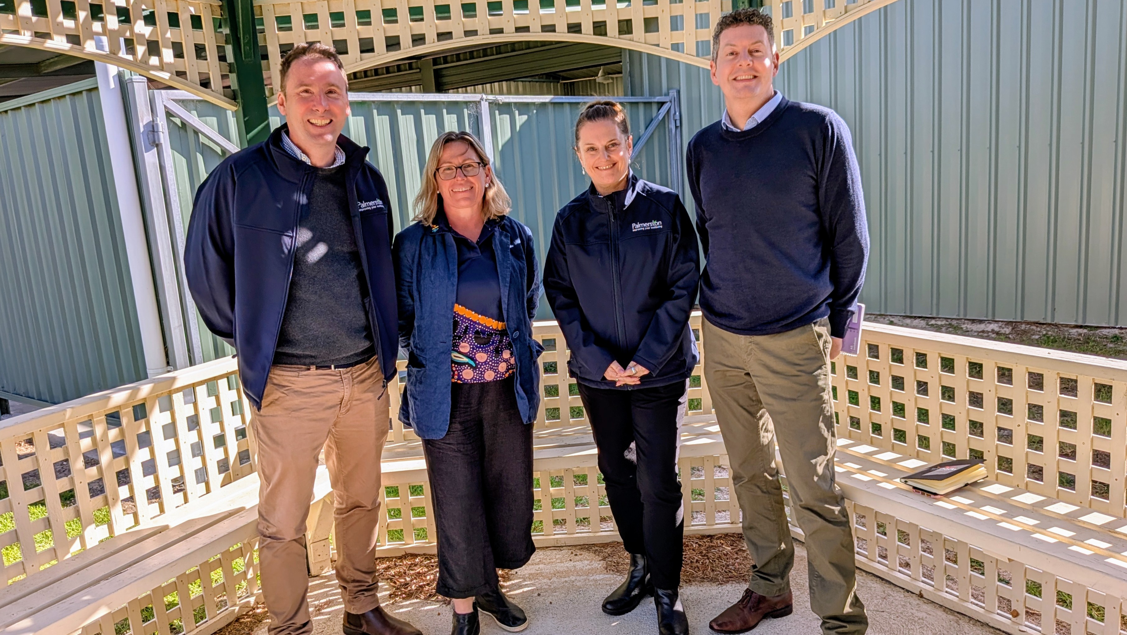 Image of four people in casual where standing under a house patio