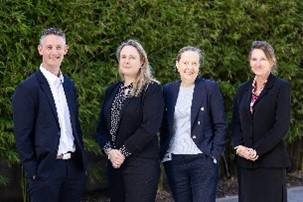 A man and three women in suits standing in a row.