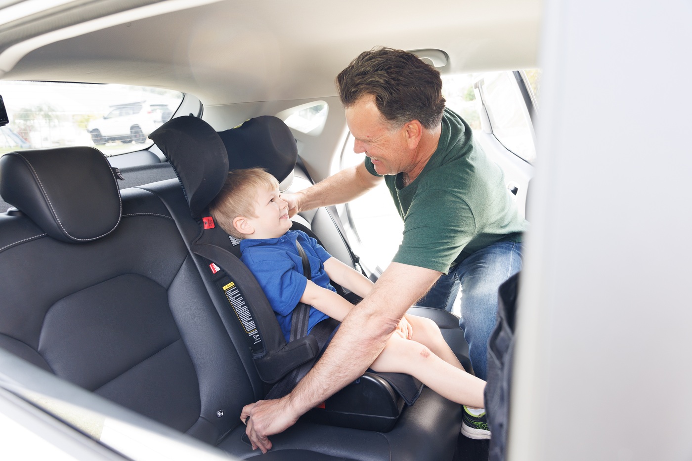 Child in a car seat while father buckles seatbelt