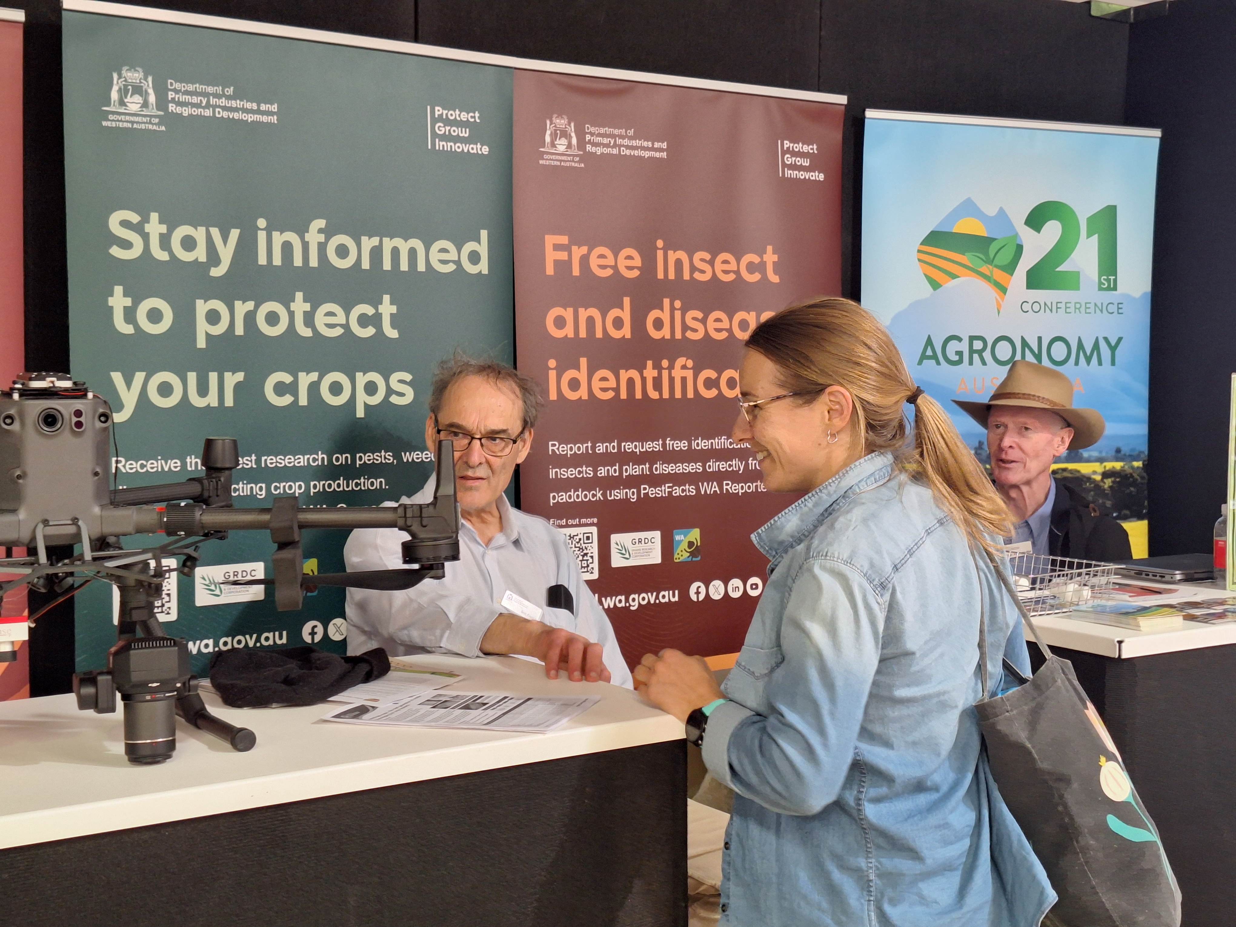 A woman talking to a man, both looking at a drone in a display.