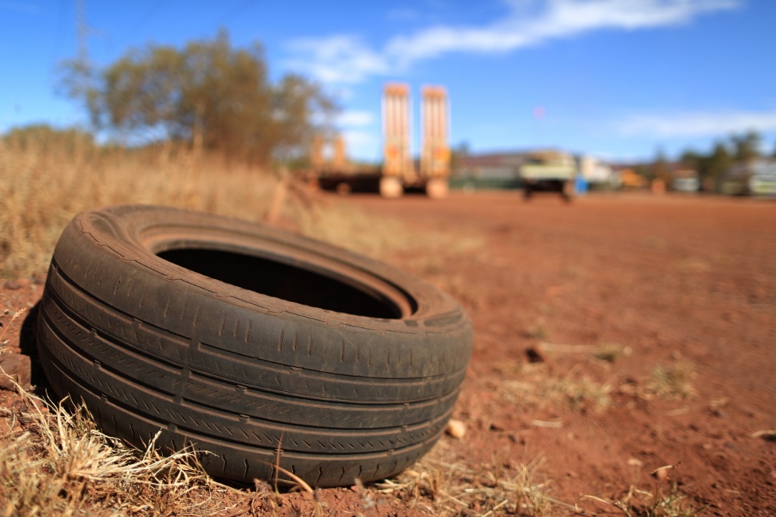 Picture of an old discarded tyre on the side of a red dirt road