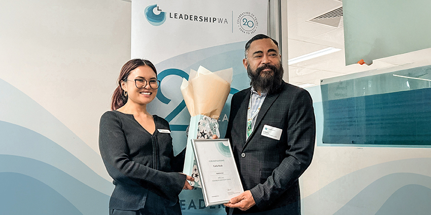 Photo of two young adults receiving awards with a Leadership WA sign in the background