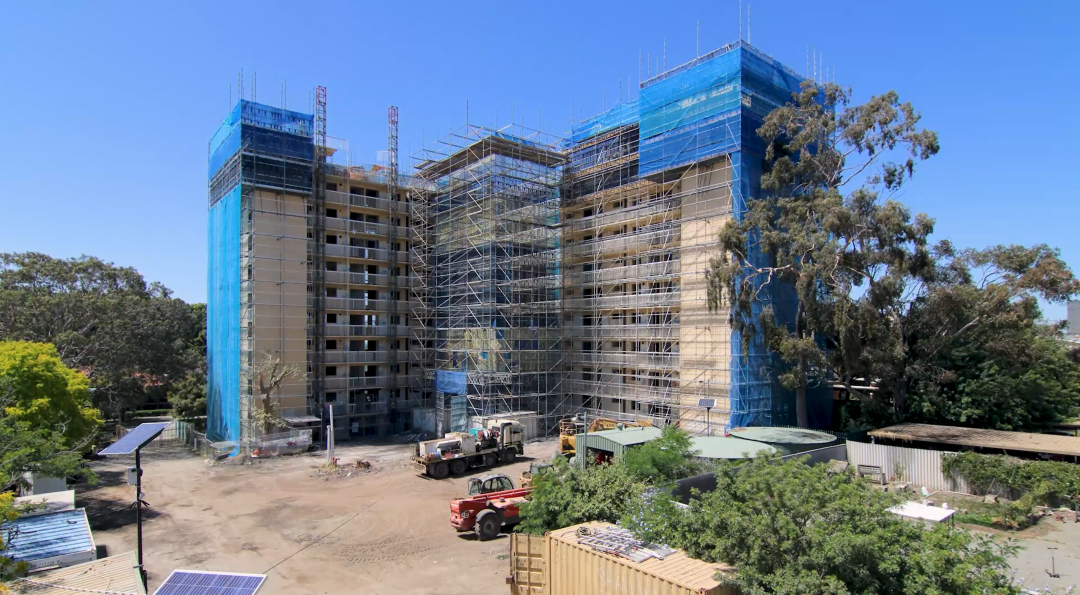 Large beige building with construction scaffolding surrounding it