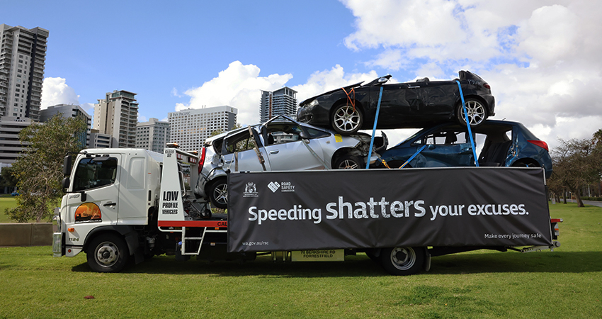 A flatbed truck with smashed vehicles piled on top.