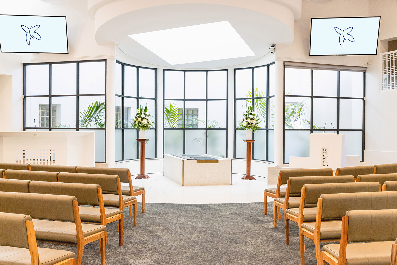 interior of a bright, white room with wood and leather pews leading up to a catafalque and podium