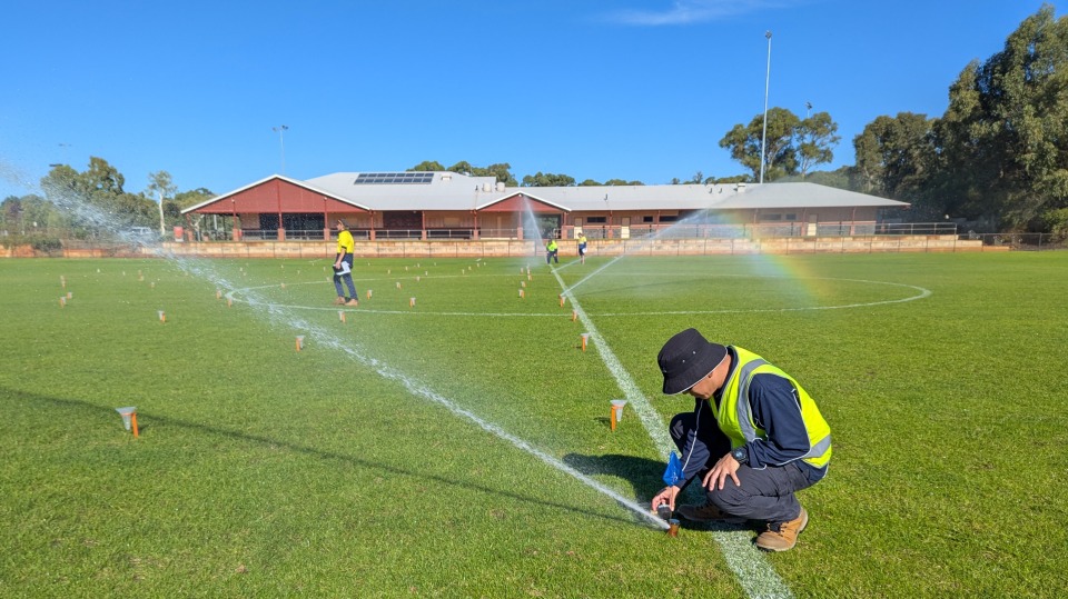 Men in hi-vis inspecting irrigation on a sports field