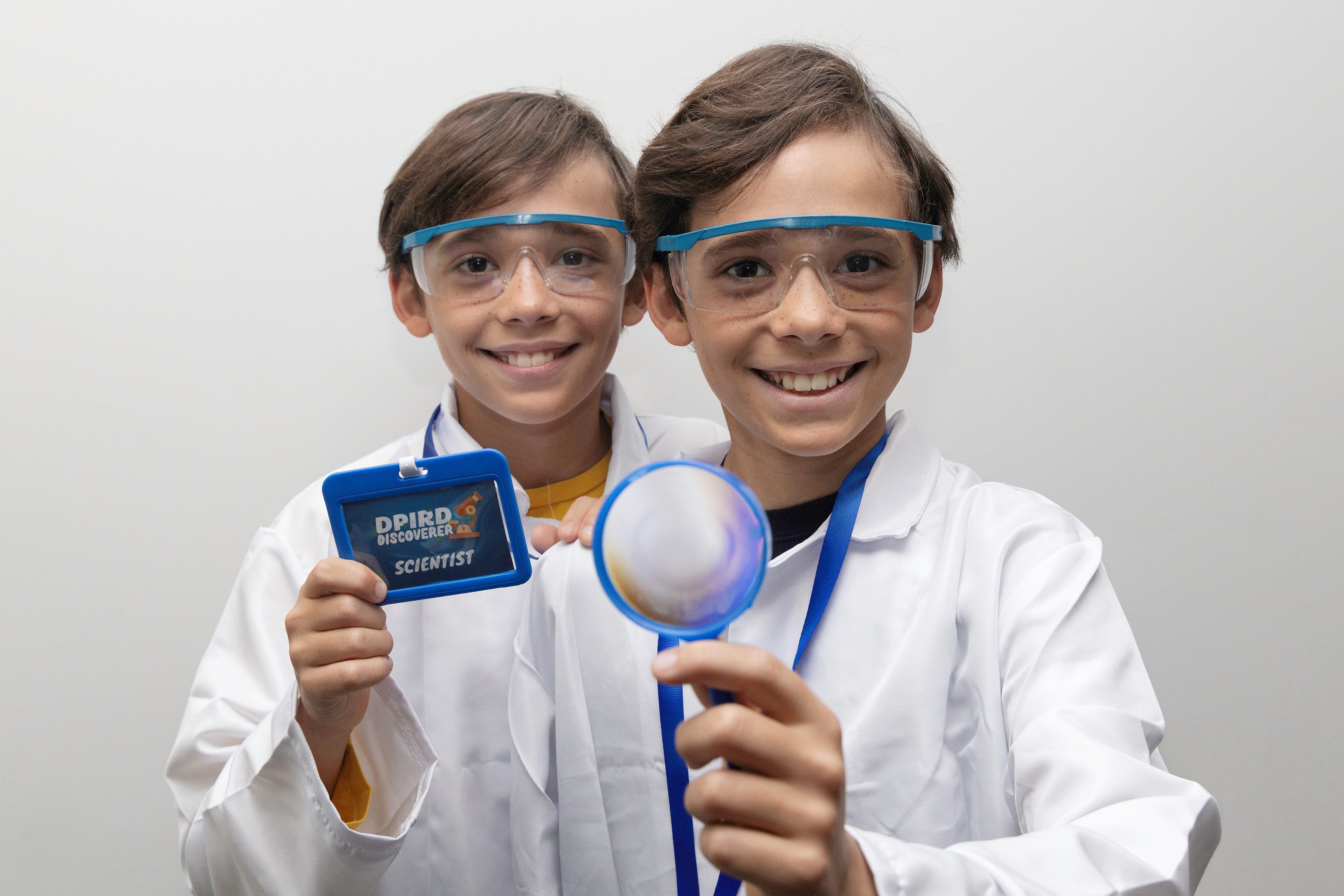 Ten year old twin boys dressed in laboratory coats and glasses.