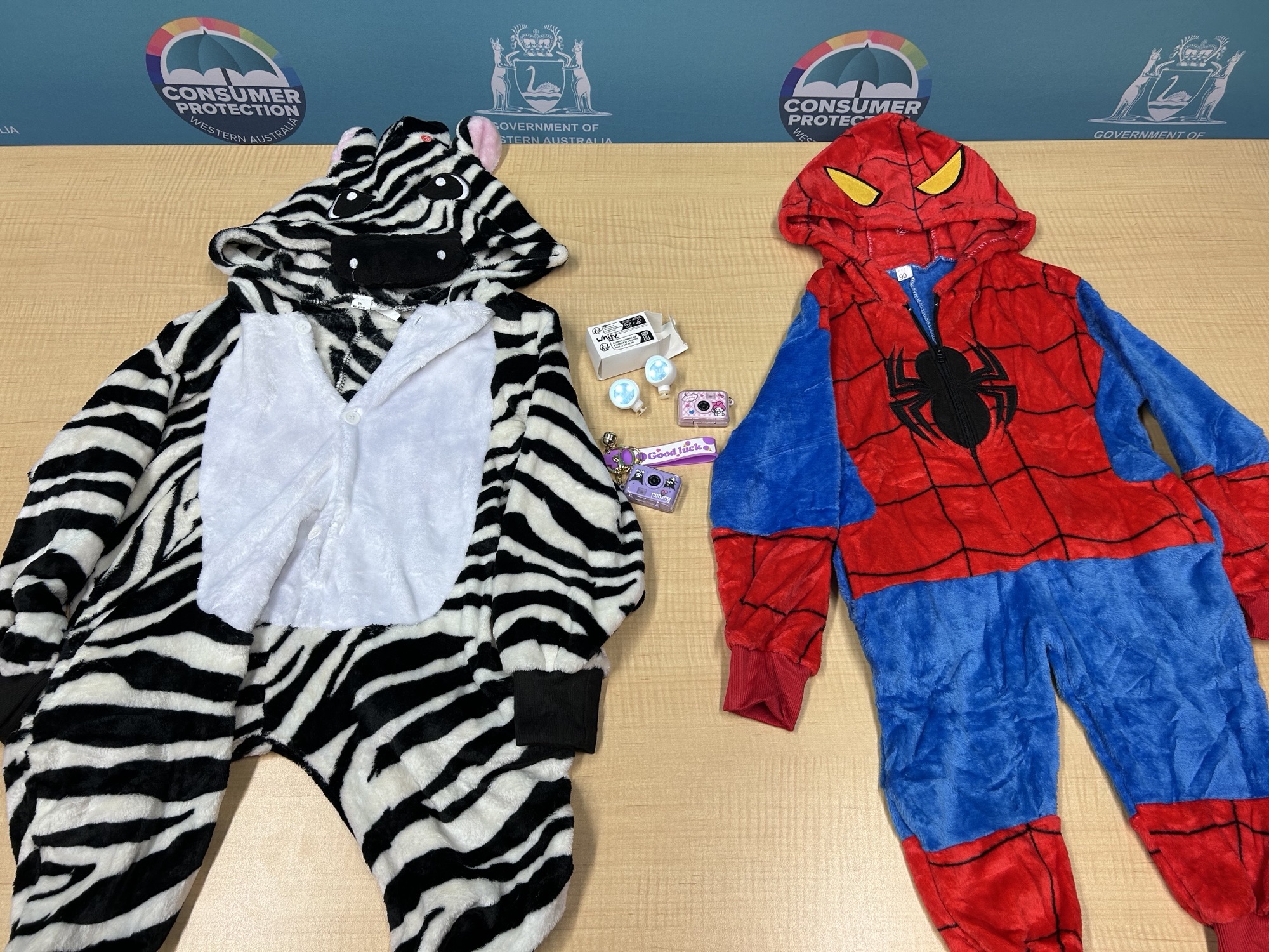Non-compliant onesies without fire hazard labelling and mini cameras and shoe charms without button battery safety warning information
