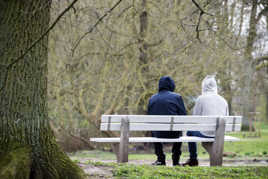 Two people in hoodies sitting on a park bench