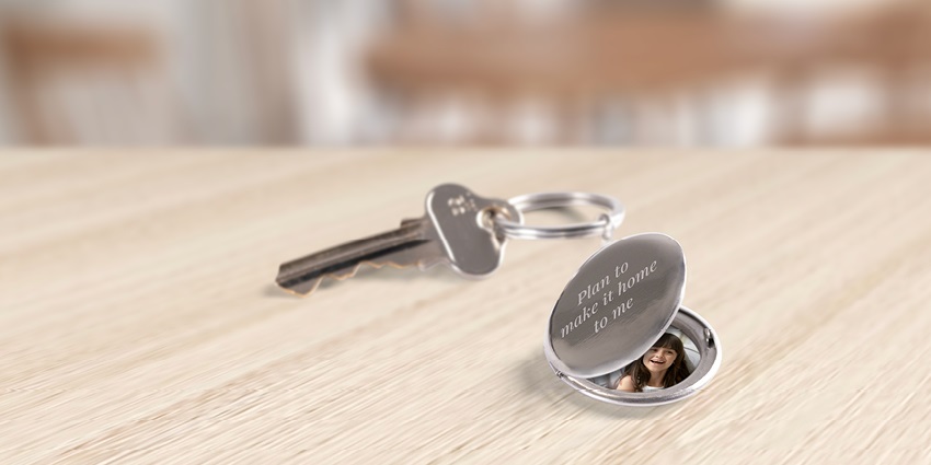 A key attached to a locket with a photo inside and an engraving that says, Plan to make every journey safe