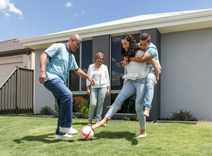 Photo of family kicking a soccer ball who have built a new house