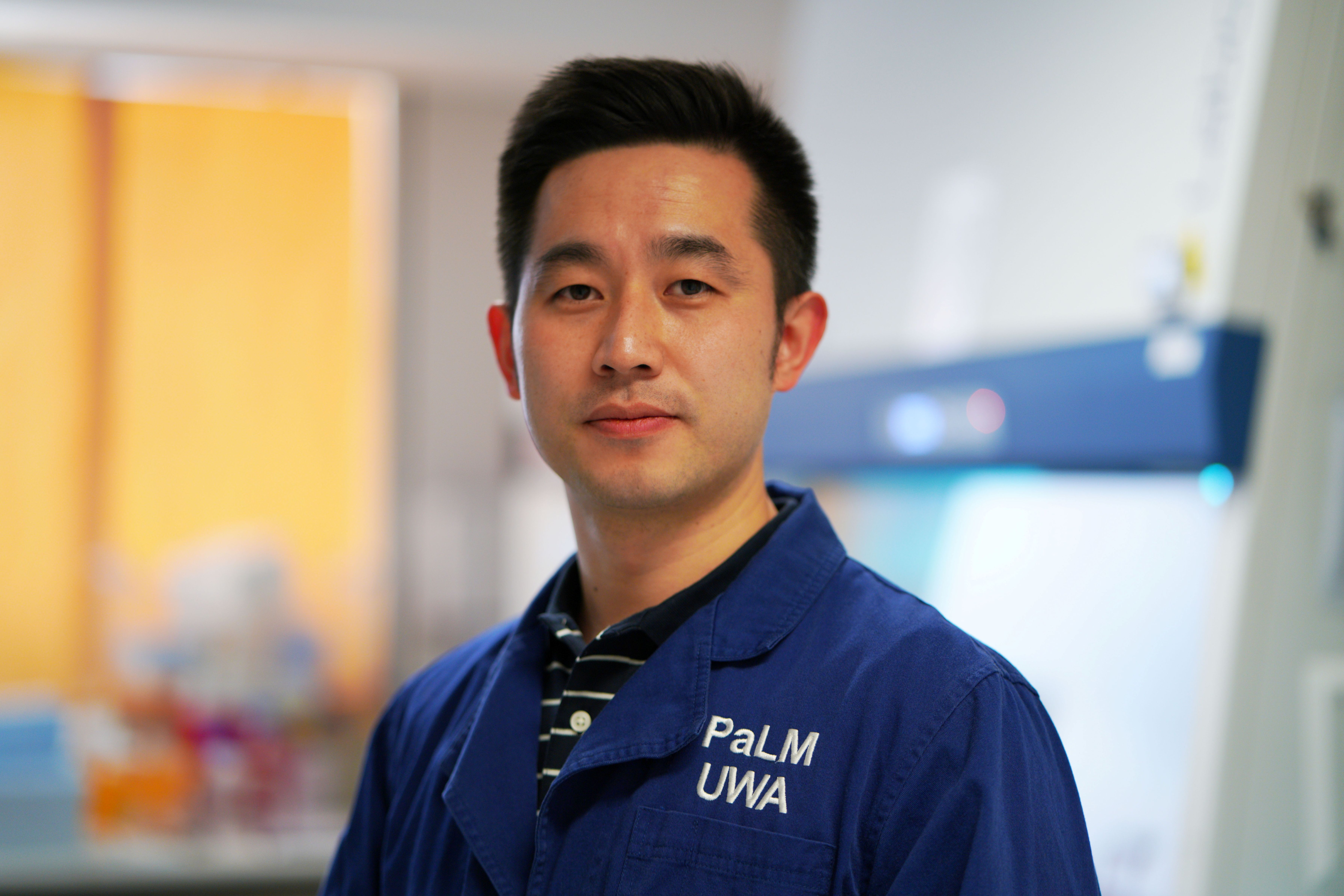 psa finalist kai chen in a lab standing with PaLM lab coat on