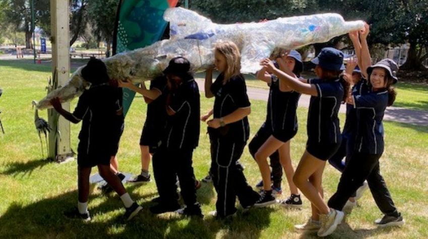 Primary school students carrying a scrap dolphin filled with rubbish collected during River Rescue Day.