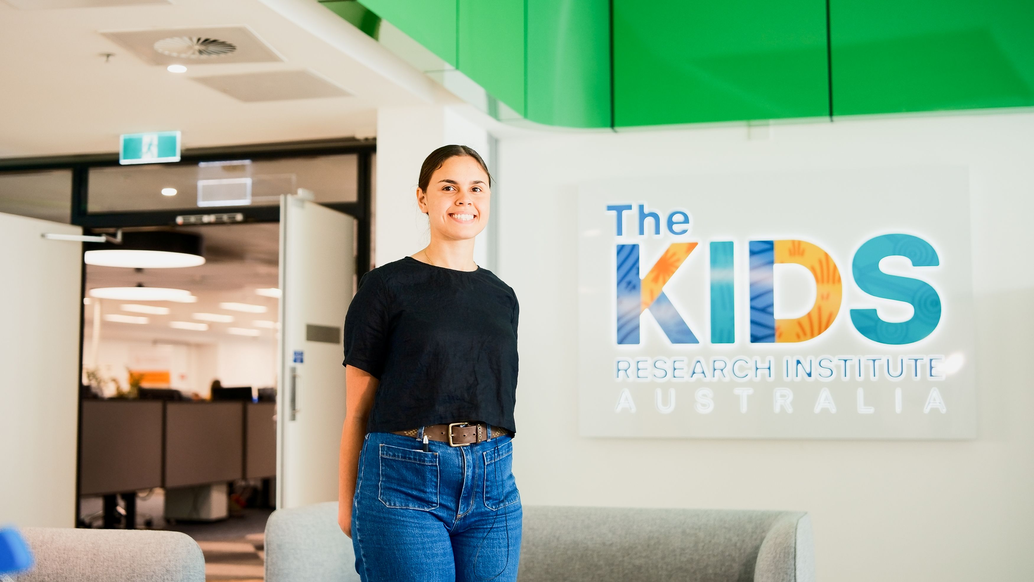 Taleah standing in front of The Kids Institute sign 