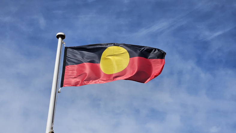The aboriginal flag waving in the wind, with blue sky in the background